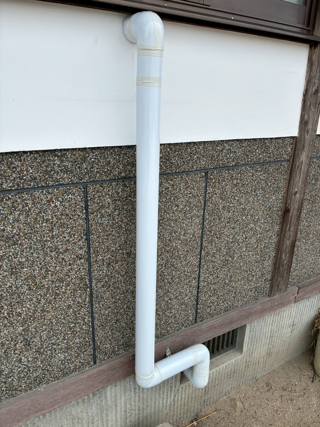 施工後の外壁に白いVP管が縦引きでスッキリ設置されたアフター