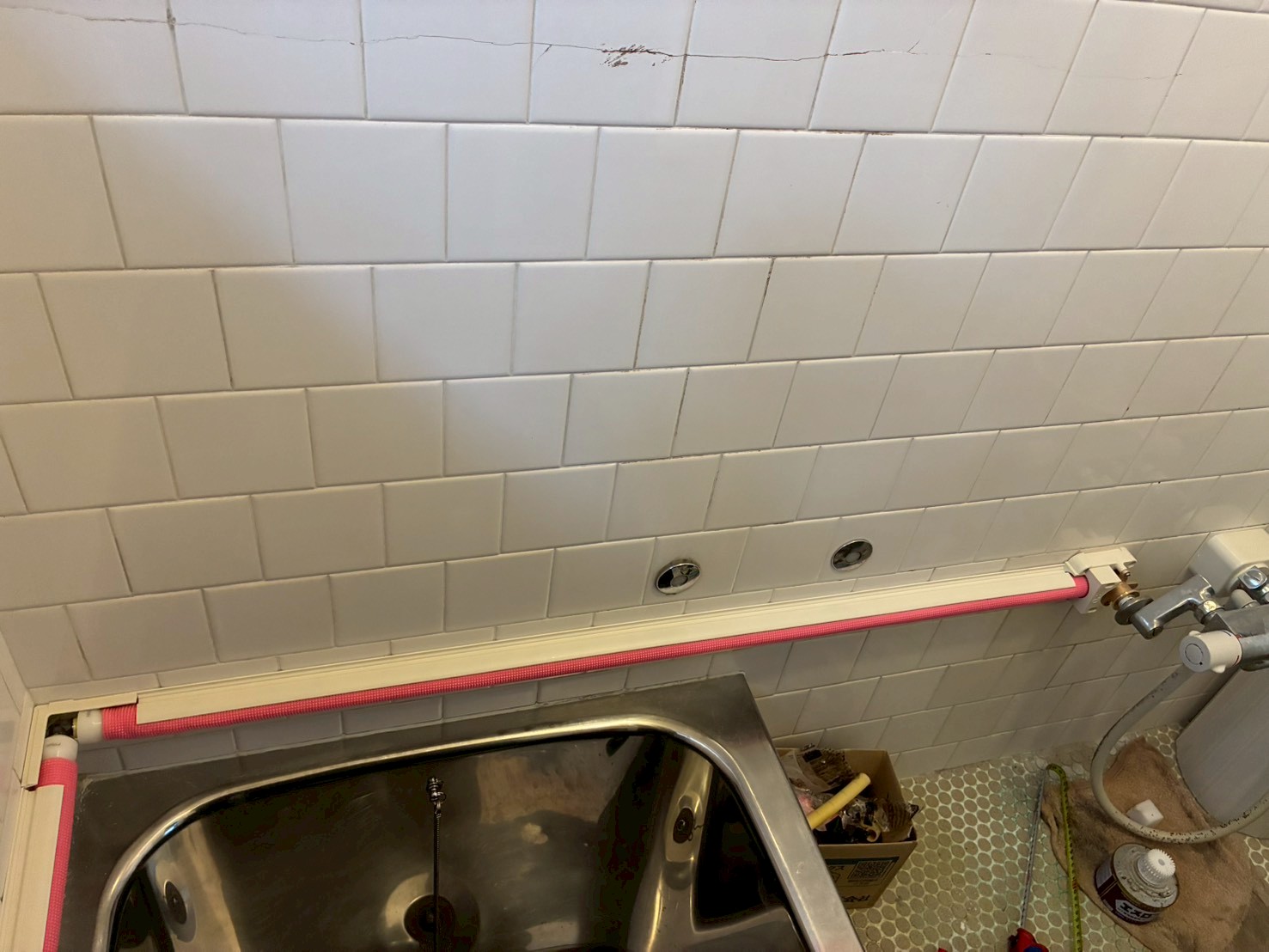 浴槽エプロン沿いに架橋ポリエチレン管(ピンク管)を横引きしているところ